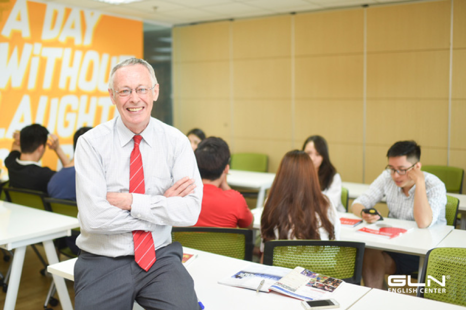 A person in a red tie sitting at a table with his arms crossed
Description automatically generated