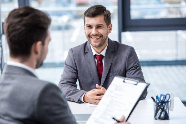 A person in a suit smiling at another person

Description automatically generated